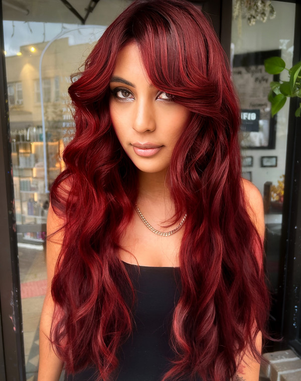 41 Red Hair Colours You’ll Adore: Radiant Crimson Long Waves with Curtain Bangs