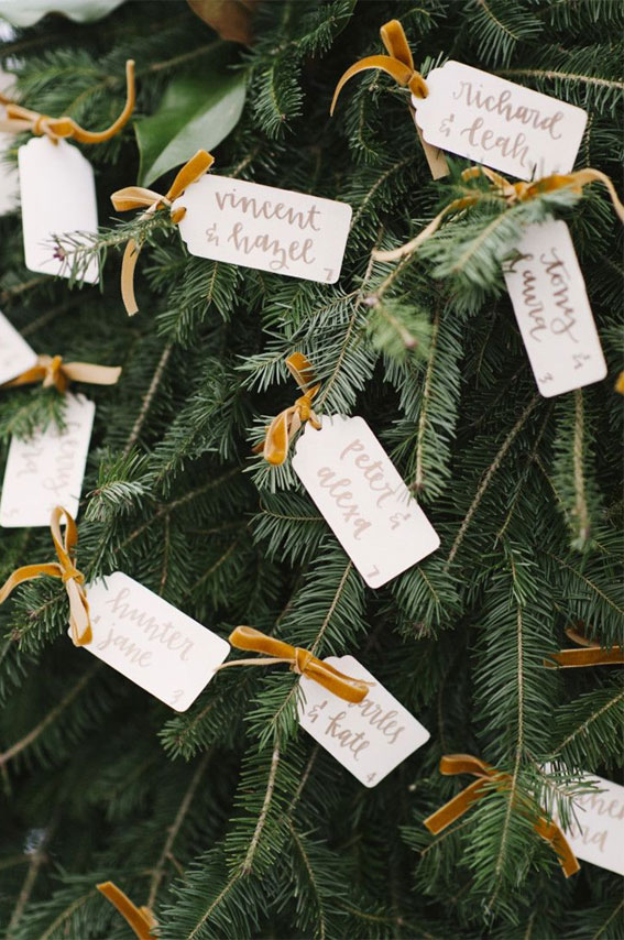 Simple white tag as escort cards hang on Christmas tree , winter wedding ideas